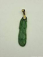 Front view of the carved green jade pendant with an 18K gold bail.