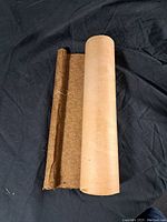 Rolled Asian scroll laid flat on a dark fabric background showing the fabric backing and scroll paper.