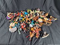 Top view of mixed vintage toy figures piled together with various characters including a large cartoonish head figure and dinosaur toys.
