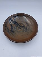 Top-down view of brown ceramic dish showing black speckled glaze pattern inside the bowl