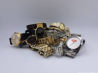 Bulk lot of assorted vintage wristwatches stacked, showing a mix of dial colors and strap types including metal and fabric.