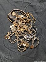 Pile of mixed vintage wristwatches in gold and silver tones with various styles and sizes.
