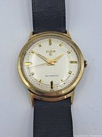 Front view of Elgin automatic wristwatch showing gold-tone case, white dial with gold markers and hands, brand and self-winding text.