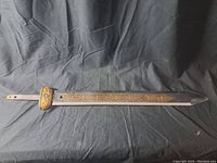 Full view of the prop sword showing engraved gold-colored blade and pointed tip
