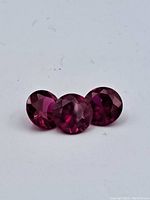 Three round faceted rubies on a white background