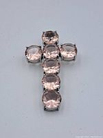 Front view of sterling silver cross pendant with seven round pink stones arranged in cross shape.