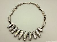 Complete front view of the vintage sterling silver pearl necklace displayed flat, showing the unique elongated baroque pearls and silver chain.