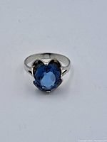 Front view of a vintage sterling silver ring with a large blue faceted oval stone set in a claw setting.