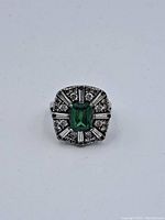 Top view of sterling silver ring showing green center stone and clear accent stones arrangement.