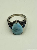 Top-down view showing teardrop-shaped blue center stone flanked by two smaller blue stones and detailed silverwork on shank