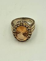 Top view of vintage sterling silver ring with a large oval pink faceted stone surrounded by a halo of smaller clear stones, showing detail of the setting and stones.