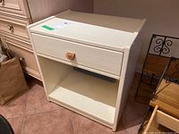 Frontal view of the painted wood cabinet showing drawer with leather pull and lower storage shelf.