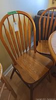 Single wooden dining chair with spindle back and contoured seat, natural wood finish.