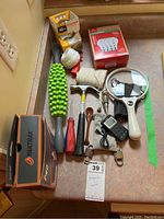 Top down image showing assorted household items including tools, Yaktrax box, light bulbs, twine, and measuring device