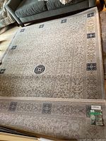 Full view of beige Hayim patterned rug with central arch motif and navy square medallions under sofa