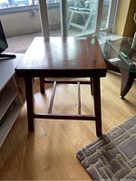 Front view of the wooden side table showing legs and floor beneath.