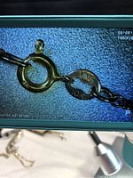 Close-up photo showing the necklace clasp with the 10K gold stamp on the clasp ring and tag.