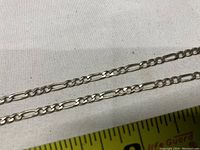 Close-up of the Figaro chain links showing the pattern and silver texture.