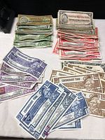 Overview showing multiple denominations of vintage Canadian Tire money notes laid out in piles: 1 dollar (blue), 5 cent (green), 10 cent (red), 25 cent (purple), 50 cent (brown).