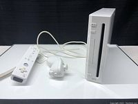 White Nintendo Wii console with slot-loading disc drive and power/reset buttons.