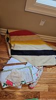 Vintage wool blanket folded on floor with vintage textiles and knitting needles laid on top