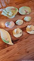 Top view of entire set on wooden surface including salad bowl with utensils, three small bowls, and two teacups with saucers