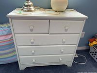 Front view of the white painted wood dresser showing five drawers and paint condition.
