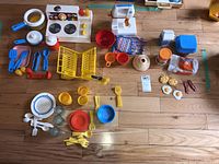 Full set laid out on the floor showing all Toy kitchen items including stove, cookware, utensils, food items, plates, cups, and containers