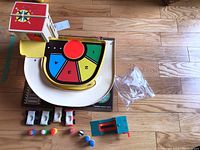 Top down and angled view of the parking lot toy with four cars, plastic figures, and accessory on wooden floor.