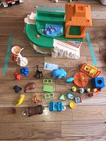 Overview photo of the vintage Fisher Price zoo playset and scattered animal figures on floor.