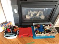 Overview of lot showing red LEGO case, clear plastic bin with loose bricks, white tub with assorted die-cast vehicles