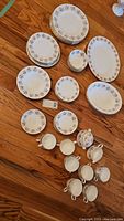Wide view showing plates, bowls, cream and sugar set, teacups, and saucers arranged on table