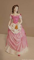 Front view of Royal Doulton Lynne HN 4155 porcelain figurine in pink dress holding a small brown fan.