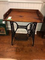 Front view of the table showing the wooden tray top and Singer sewing machine base