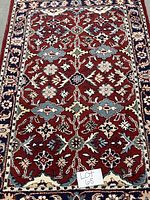 Full view of the red, cream, blue, sage, and brown patterned area rug with Lot 68 note.