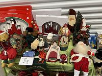 Photo of assorted Christmas decorations featuring teddy bears, dolls, Santa figurines, and two Norwegian wooden candle arches with light-up function in white and red.