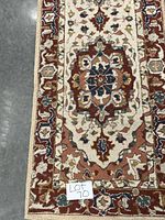 Close-up of the runner rug's detailed floral medallion pattern and border in red, cream, blue, and beige colors.