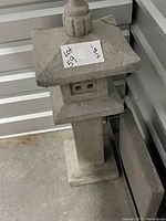 Front and angled view of the garden statue showing its pagoda-style roof and repaired corner.