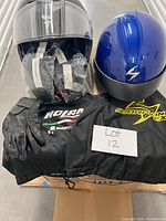 Photo showing two size XL motorcycle helmets, one black Nolan helmet and one blue helmet with 'S' logo. Multiple sealed visors, extra padding, storage covers/bags are also present. Black leather gloves placed in front.