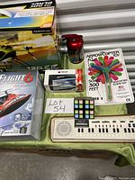 Photo showing the boxed Blade 120 S2 RC helicopter, boxed Real Flight 6 RC boat, mini RC firetruck box, Arrowcopter hand helicopters toy, red fire extinguisher object, small multicolored cube puzzle, Casio handheld keyboard with speaker, and Casio VL Tone handheld keyboard.