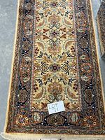 Top view of runner rug showing floral medallion pattern and fringed end with lot label