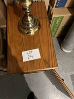 Wood side table with a brass lamp base on top, showing the wood grain and lamp base detail.