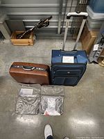 Overview of two Samsonite suitcases and two silver travel hanging bags.