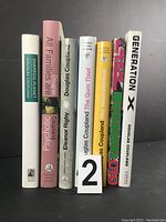 Six books by Douglas Coupland standing upright showing the front and spine titles.