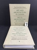 Two hardcover books titled 'Art and Architecture in Canada' lying flat, showing cover details with bilingual text and authors.