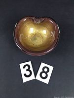 Top-down view of the iridescent blond glass ashtray showing its rounded shape and glossy surface with some chips visible.