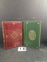 Two classic hardcover books, one red with ornate gold embossing, one green with gold floral embossing and oval design.