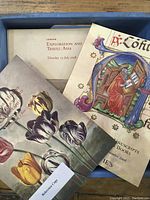 Photo of varied auction catalogs with detailed floral and medieval illuminated manuscript cover art