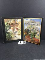 Front view of two vintage hardcover books: The Yearling and The Boy's King Arthur, showing colorful illustrated covers.