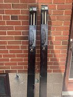 Photo showing two unopened boxed sets of Creations Adjustable Double Rod Sets against a brick wall, each package containing double curtain rods with 1 1/8 inch diameter poles.
